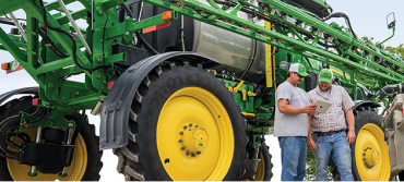 Large John Deere with two people discussing in front of it