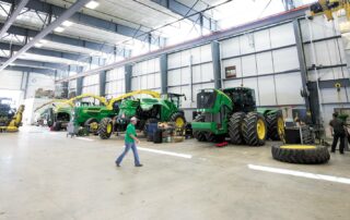 farmer walking past large John Deere tractors