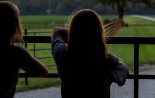 two women looking past a fence